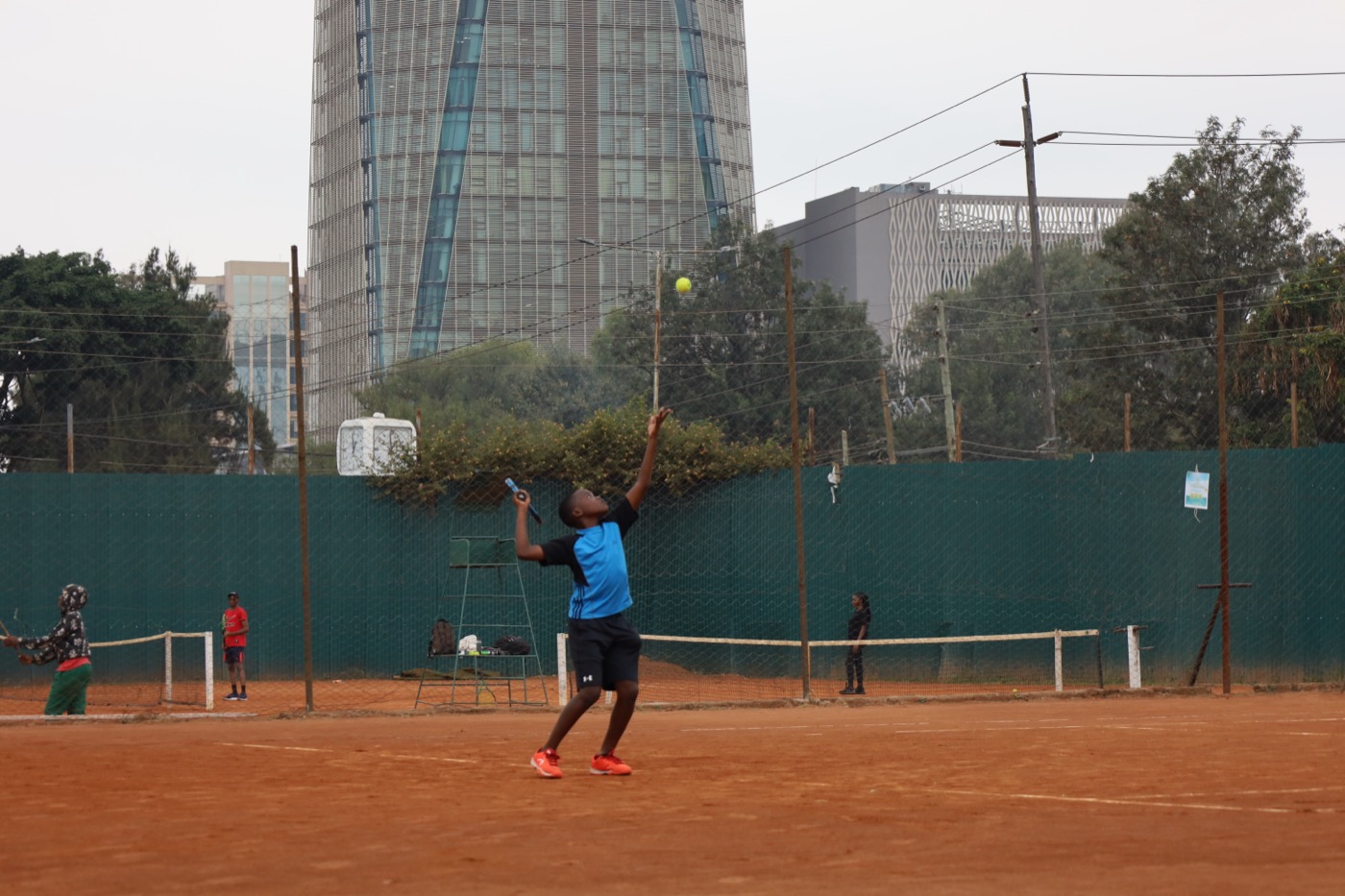 Player mid-serve with the city skyline behind the court