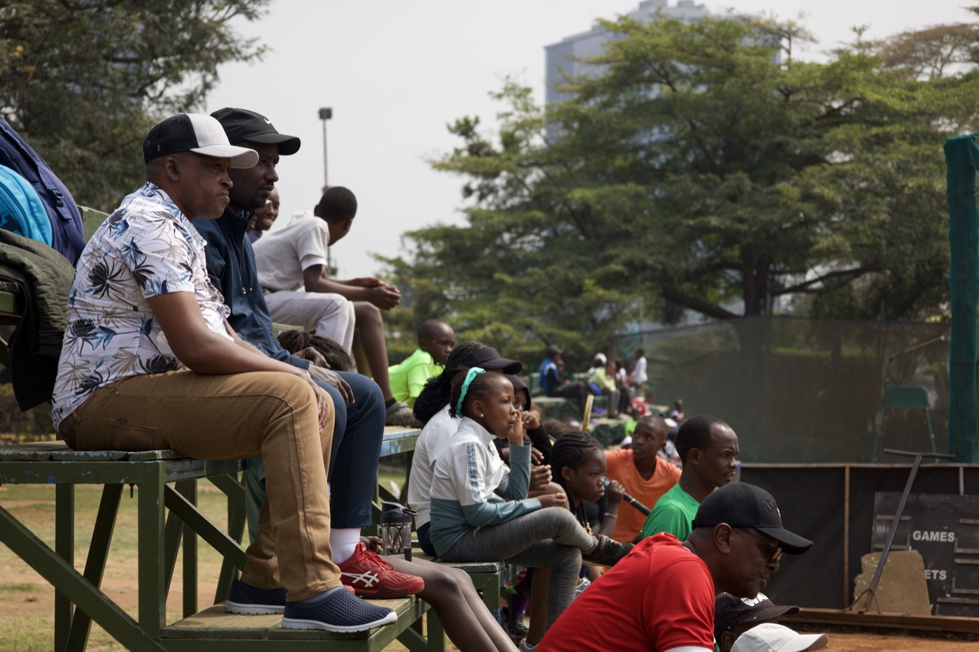 Spectators watching intently from the bleachers, city skyline in the background