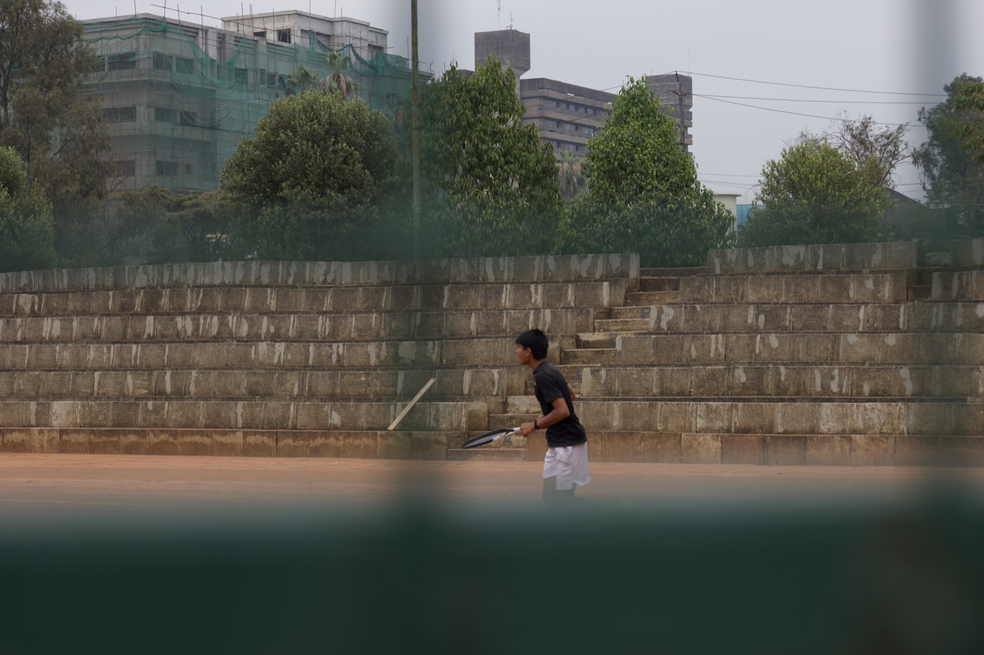 Player walking down stone terrace steps with the city skyline behind