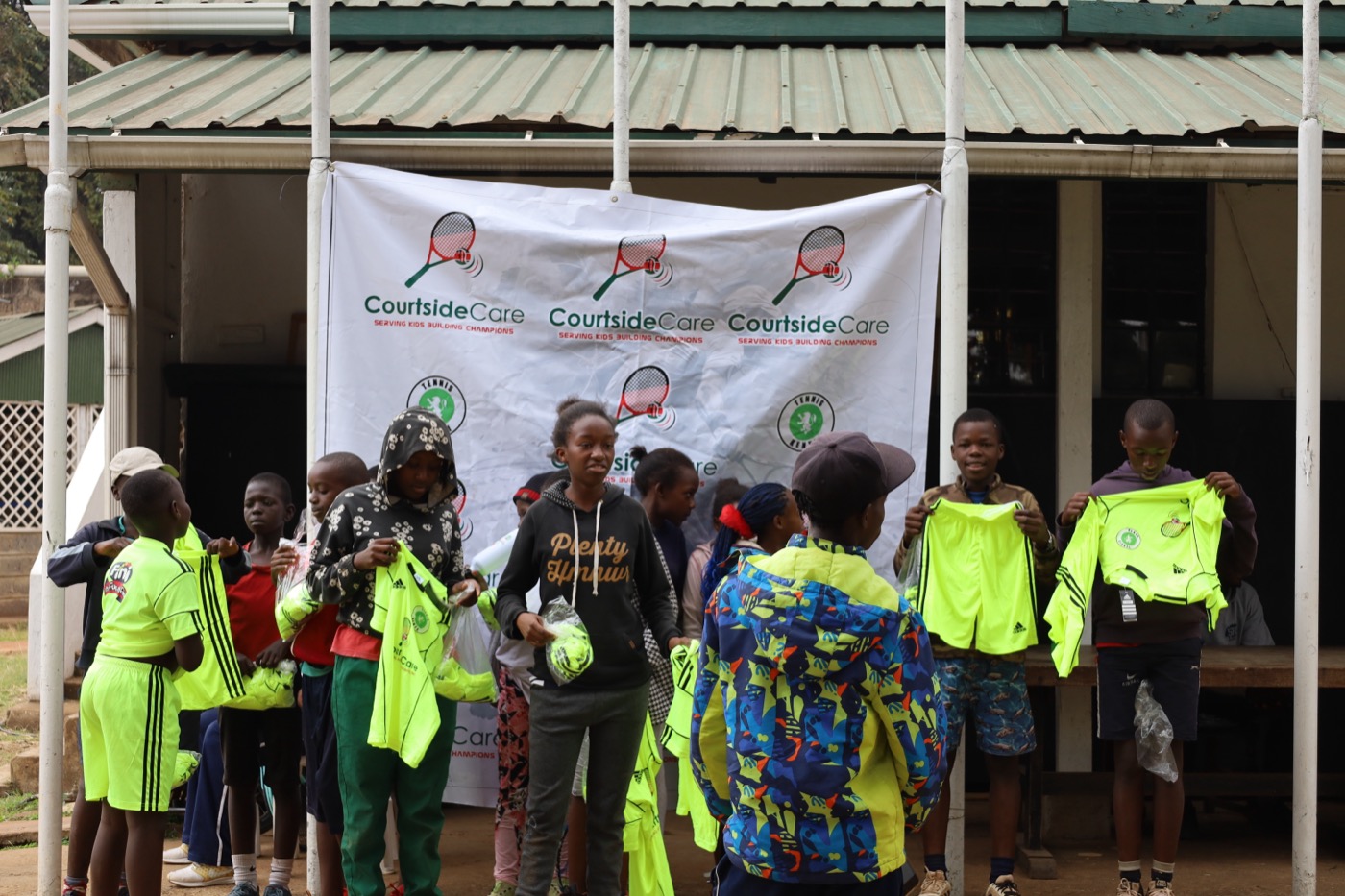 Young athletes gathered around the Courtside Care banner holding up their jerseys